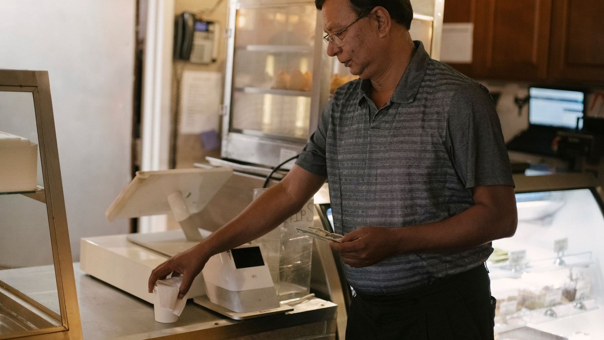 เจ้าของร้านชาวเอเชียยืนอยู่หลังเคาน์เตอร์คิดเงิน